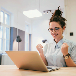 E-Learning: Frau freut sich am Laptop über Lernerfolg