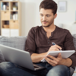 Learning Nuggets: Mann sitzt mit Laptop und Schreibblock auf der Couch und lernt